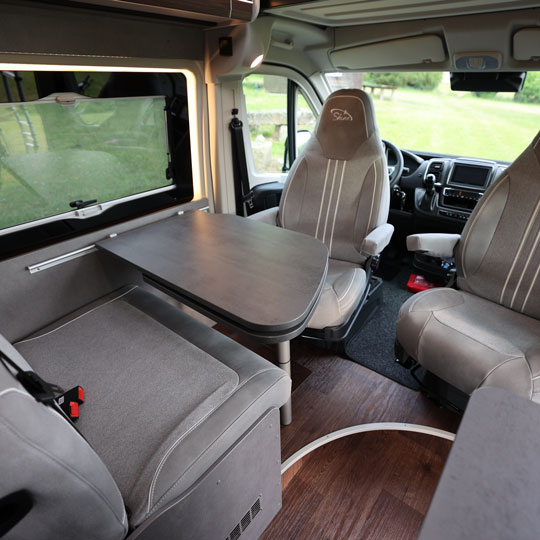 Moderner Innenraum des Pössl Campervan mit Esstisch und drehbaren Sitzen – komfortabel reisen und unabhängig campen.